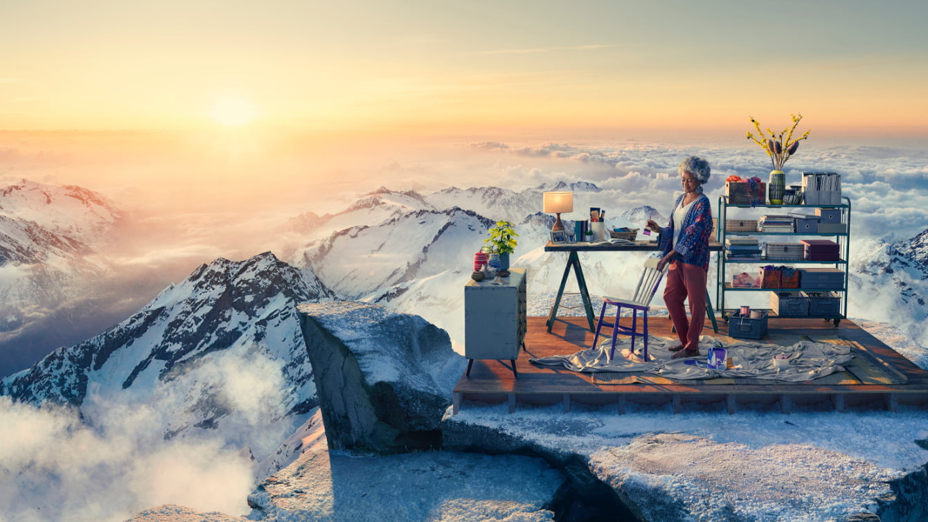 Image of woman on mountain top painting chair