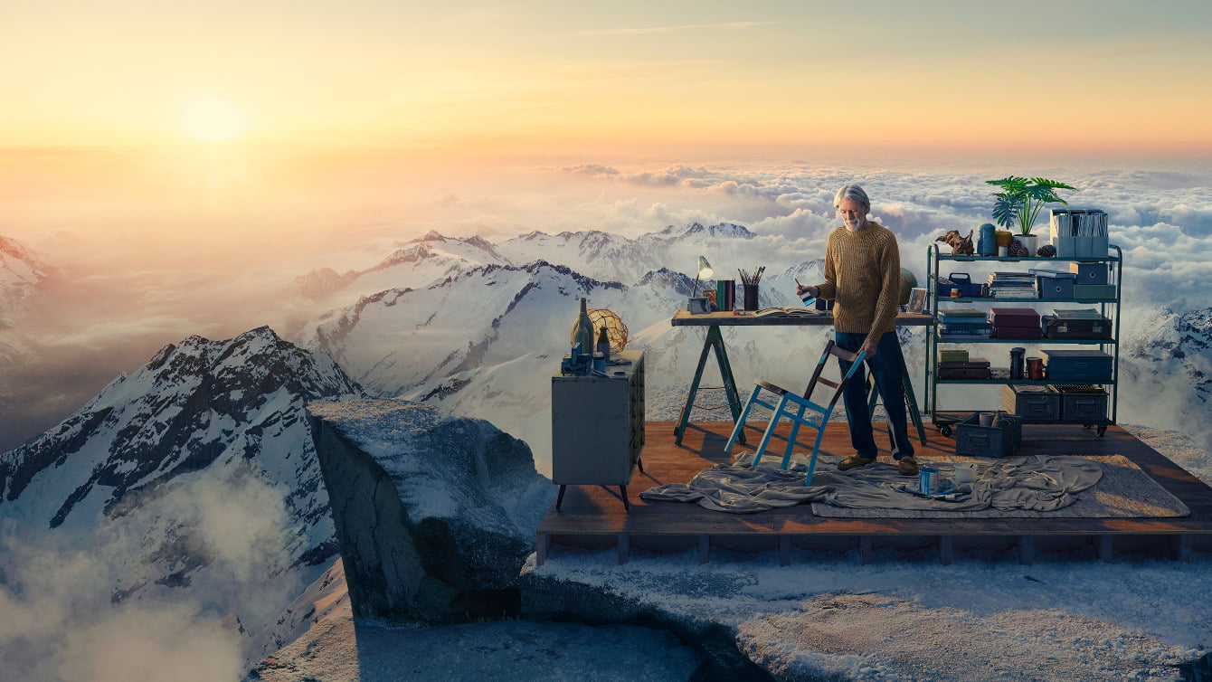 Image of man on mountain top painting chair